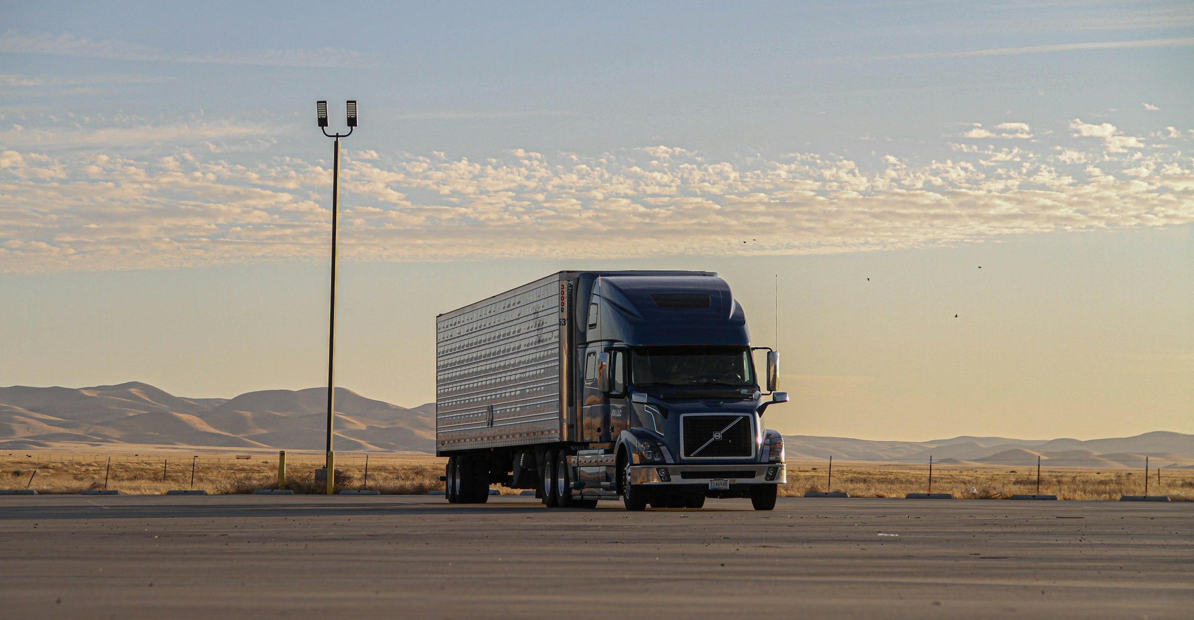 Semi-truck driving down a desert highway at dusk